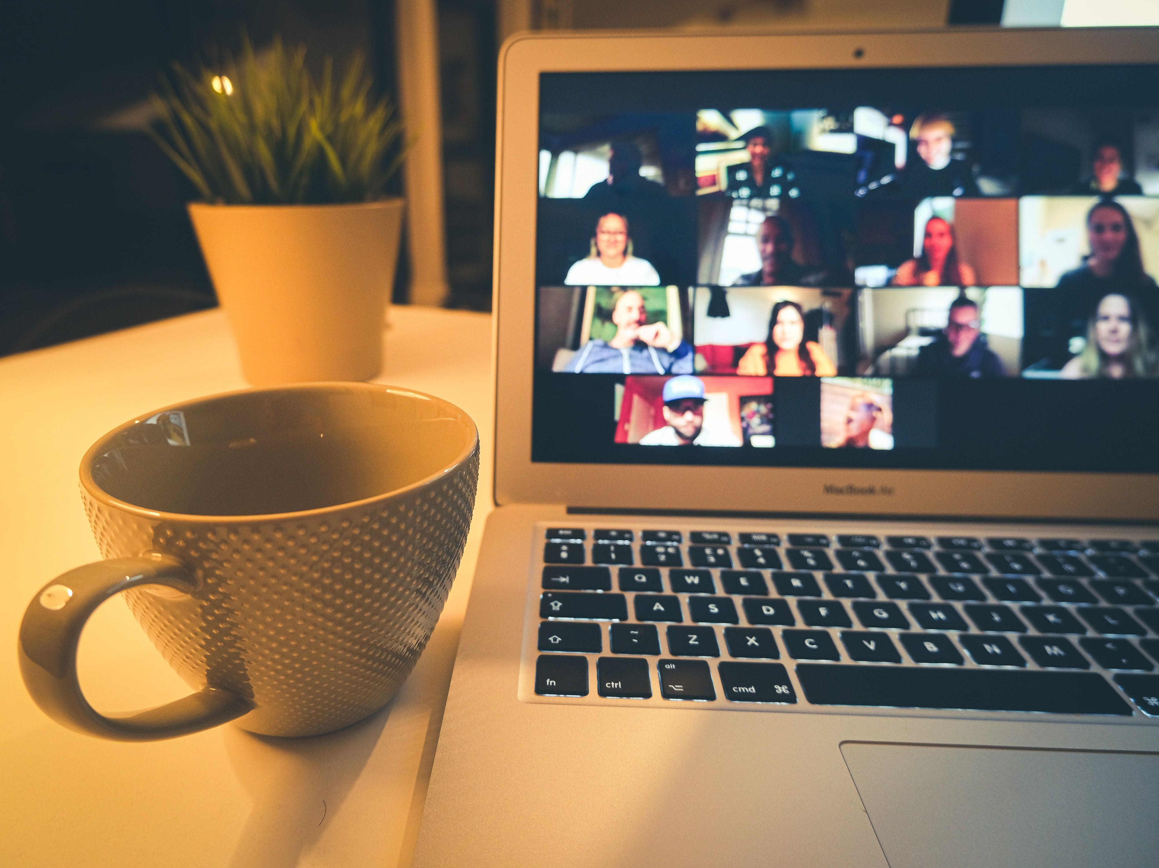 A Zoom meeting on a laptop next to a coffee cup